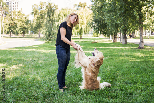 woman and retriever on a background of green grass in the fresh air.
