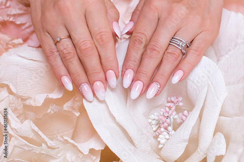  Female hands with ombre manicure nails, pink gel polish, on paper flowers background