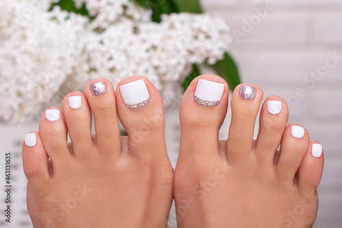 Beautiful female feet with fashion manicure nails, white an silver gel polish
