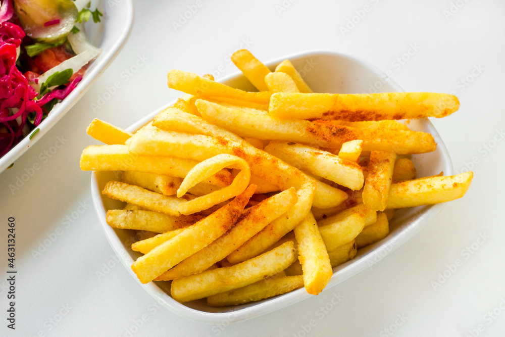 Fried french fries with paprika spice on oval plate on the white table Fried french fries with paprika spice on oval plate on the white table