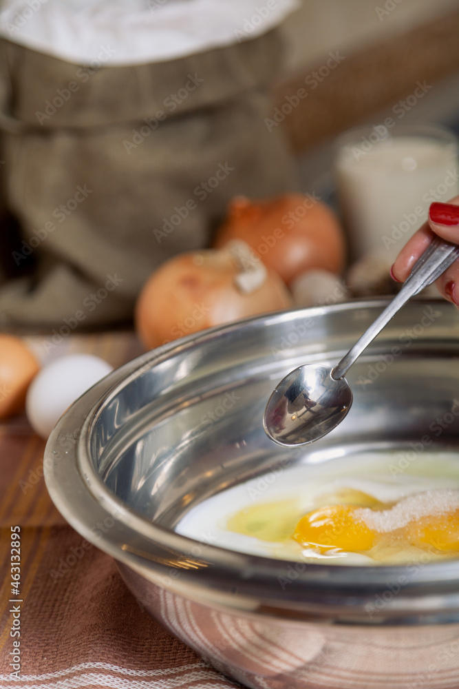 Teaspoon in woman hand over metal bowl.. Teaspoon in woman hand over metal bowl..