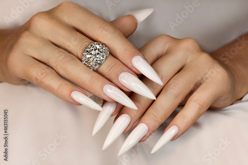Long light manicure with jewelry on a woman's hand. photo