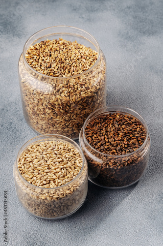 three containers of malt on a gray background