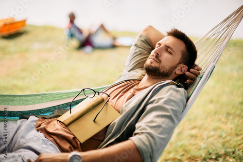 Photography Relaxed man takes a nap in hammock while spending day in nature.