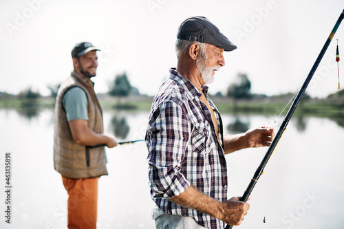 Mature man and his adult son spend time together and fish on the river.