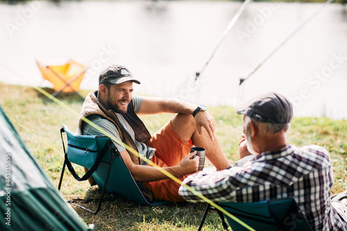 Happy man talks to his father while fishing during their camping day.