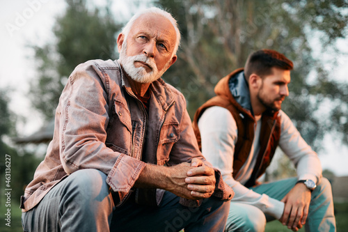 Obraz na plátně Displeased senior man has disagreement with his adult son in nature