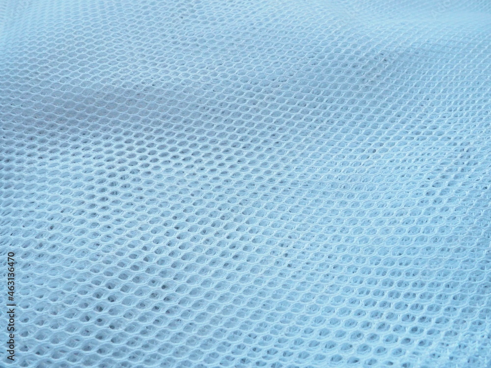 Fototapeta Sheer white net-like tulle. The mesh fabric is folded in waves. Close-up. White - blue veil or muslin