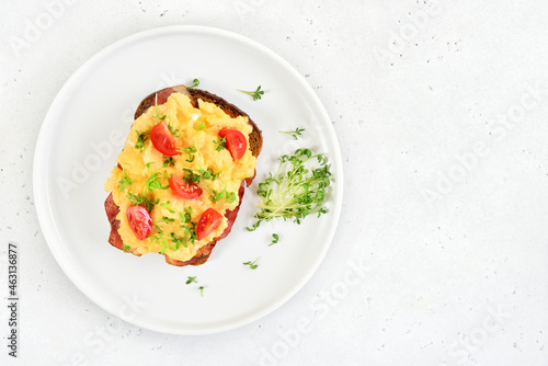 Scrambled eggs with microgreen and tomatoes on bread