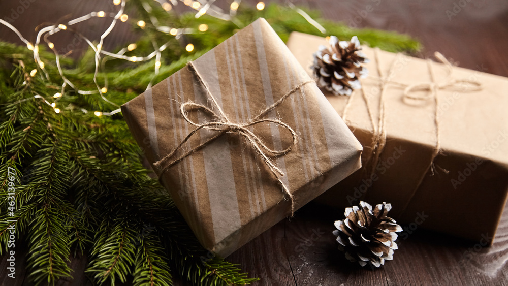 Gift boxes with Christmas light and tree branch with cones on brown wooden Gift boxes with Christmas light and tree branch with cones on brown wooden