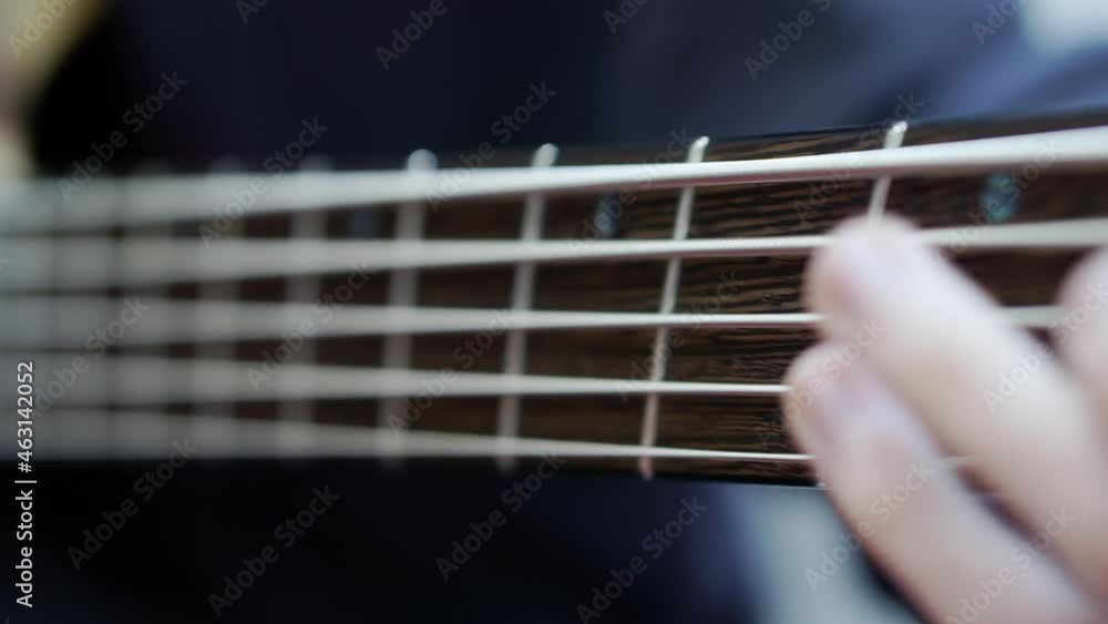 A close-up of the guitarist's fingers rearranging chords on the bass fretboard. A close-up of the guitarist's fingers rearranging chords on the bass fretboard.