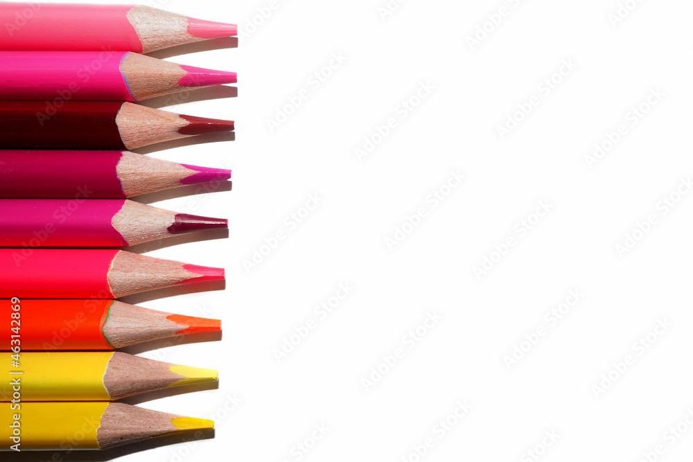 on the left, many pencils of yellow, orange and red colors lie on a white background. top view on the left, many pencils of yellow, orange and red colors lie on a white background. top view