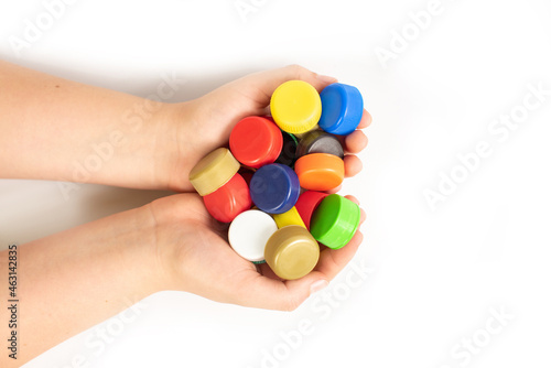 Multi-colored screw caps for plastic bottles in the hands of a child, ecology