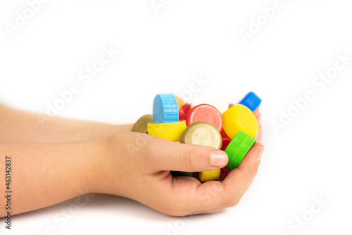 Multi-colored screw caps for plastic bottles in the hands of a child, ecology