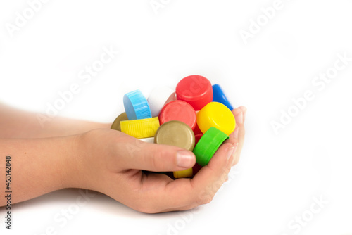 Multi-colored screw caps for plastic bottles in the hands of a child, ecology