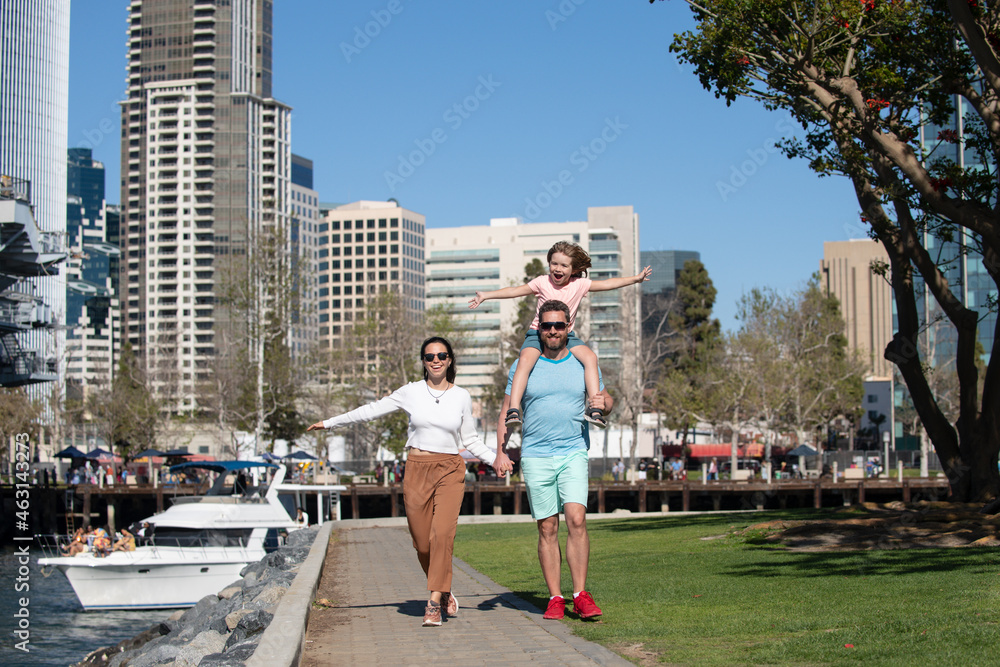 Happy family with little child son walking in modern urban city. outdoors against city landscape in San Diego.