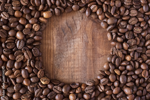 Circle made of coffee beans on a wooden surface close up.