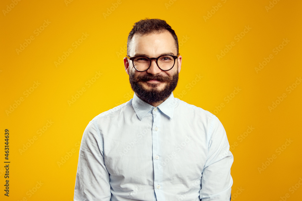 Fototapeta premium Headshot of satisfied cheerful handsome man grins at camera, glad to find suitable well paid job, isolated over yellow background