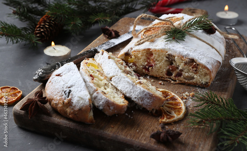 Sliced Christmas stollen with dry fruits, berries and nuts on wooden board. Traditional German treats. photo