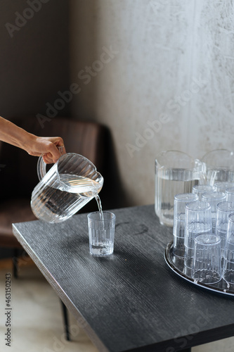 Crop woman pouring water in glass