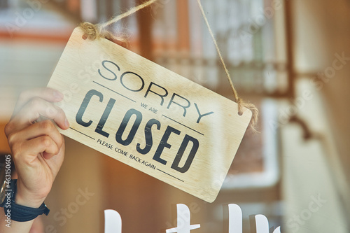 Faceless owner turning signboard on door of store