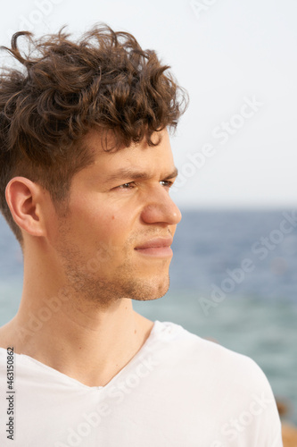 young handsome man portrait on a sea with wind in his hair. Caucasian man in white