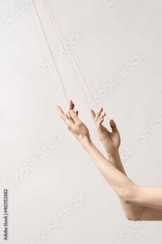 Woman's hand with red threads which symbolized control and manipulation