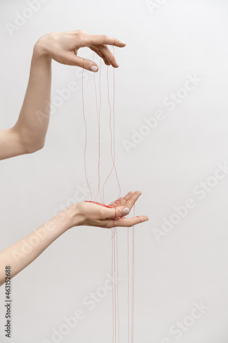Woman's hand with red threads which symbolized control and manipulation