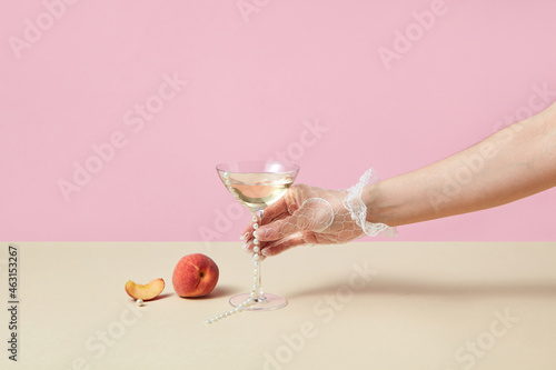 Woman in glove taking glass with drink and pearls
