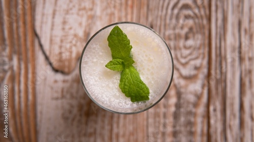 Turkish or Azerbaijan traditional Drink Ayran or Kefir with herbs and with mint in a glass on a wooden table top view. Fermented milk drink for diet. Copy space. the concept of healthy nutrition.