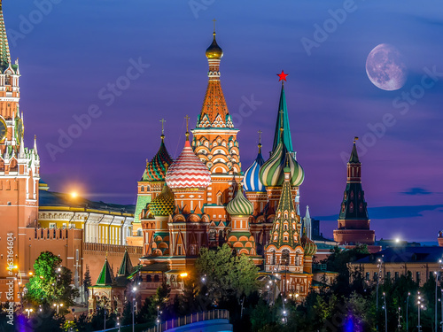 St. Basil's Cathedral against the background of the Moscow Kremlin. Colorful evening shot with Moon and purple sky for postcard or calendar. Famous tourist attraction of Russia