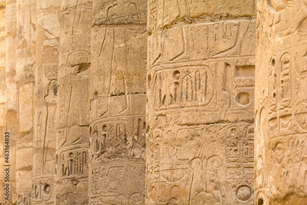 Ancient columns in a row with carved egyptian hieroglyphics 