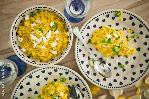 Yellow rice with greens on a cute plate with blue hearts and a table decorated with flower petals