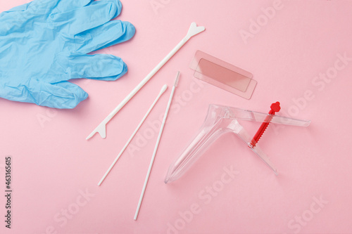 preventive gynecological examination. Prevention for womens health. Basic set for vaginal examination on pink background. Gynecological speculum,  gloves, diaper and shoe covers. Female health concept photo