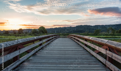 Bridge going over a river in a city park. Colorful Summer Sunset. Colony Farm Regional Park, Port Coquitlam, Vancouver, British Columbia, Canada.