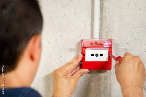 Bild auf Leinwand A back view of electrician installing fire alarm system