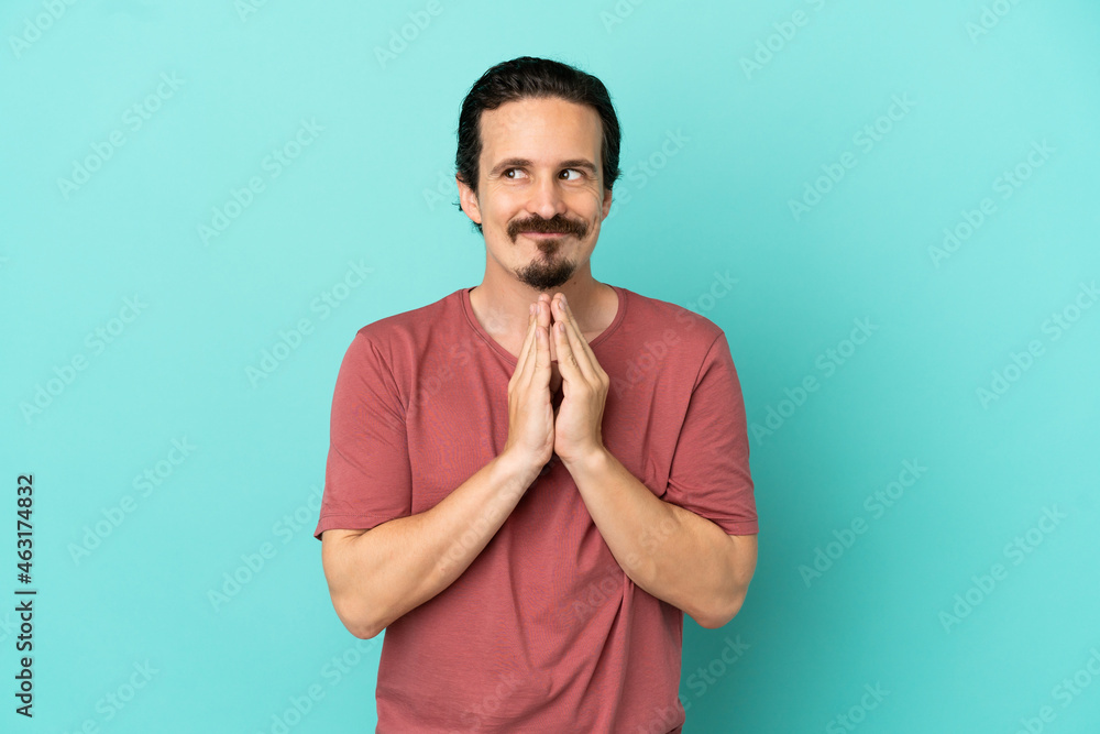 Young caucasian man isolated on blue background scheming something Young caucasian man isolated on blue background scheming something