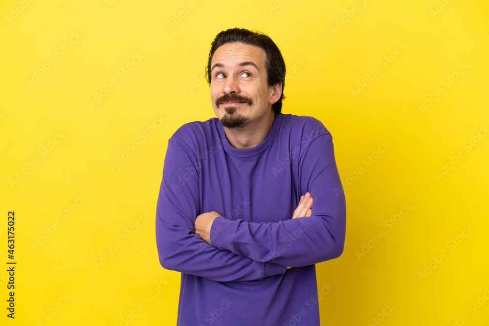 Young caucasian man isolated on yellow background making doubts gesture while lifting the shoulders Young caucasian man isolated on yellow background making doubts gesture while lifting the shoulders