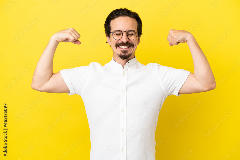 Young caucasian man isolated on yellow background doing strong gesture Young caucasian man isolated on yellow background doing strong gesture