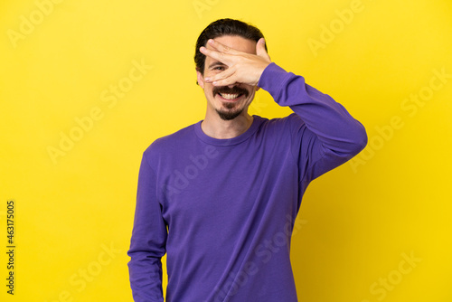 Ταπετσαρία Young caucasian man isolated on yellow background covering eyes by hands and smi