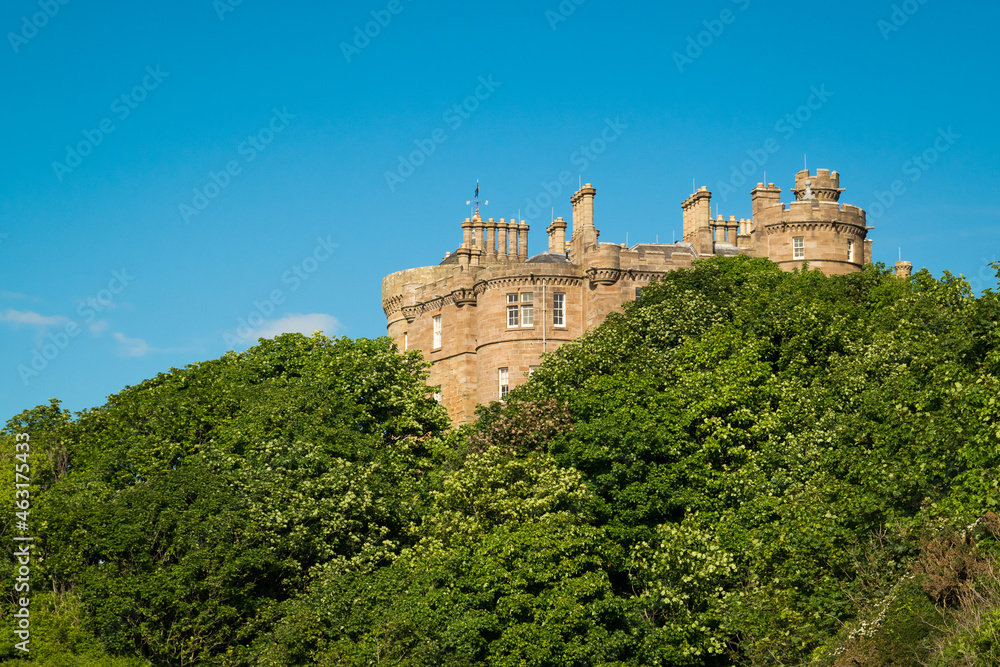 Culzean Castle peeking through the trees, seen from the beach in South Ayrshire, on the west coast of Scotland.