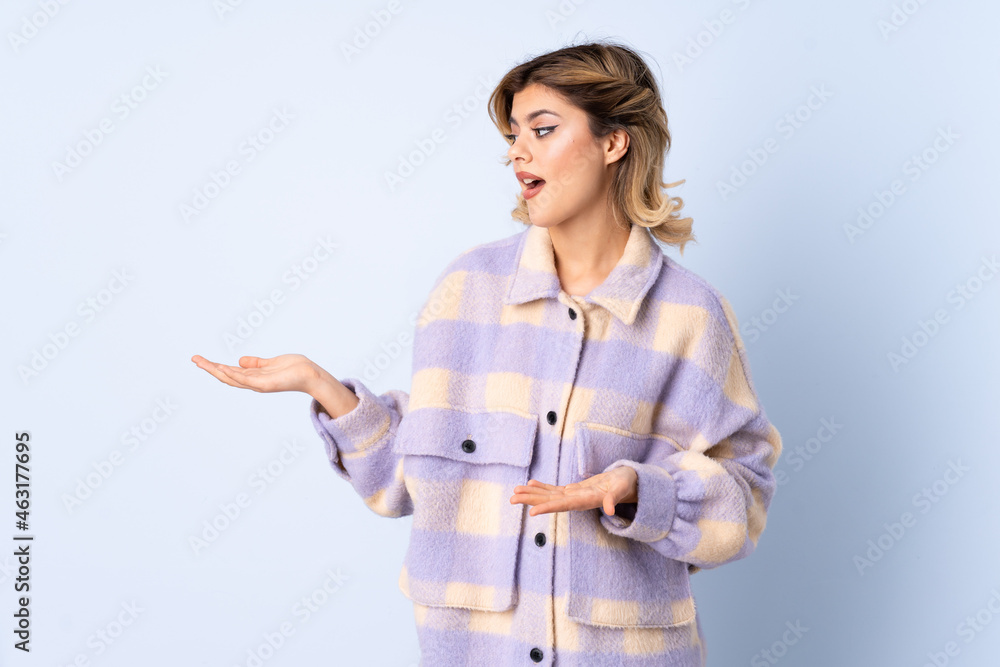 Young Russian woman isolated on blue background with surprise expression while looking side Young Russian woman isolated on blue background with surprise expression while looking side