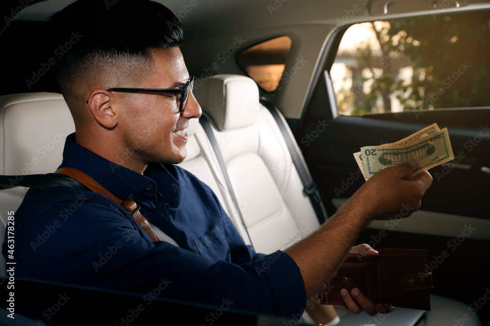 Businessman with money on backseat of modern taxi Businessman with money on backseat of modern taxi