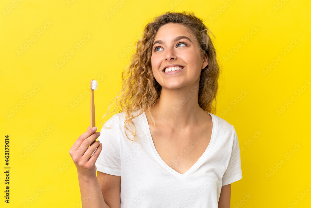 Young caucasian woman holding a brushing teeth isolated on yellow background thinking an idea while looking up Young caucasian woman holding a brushing teeth isolated on yellow background thinking an idea while looking up