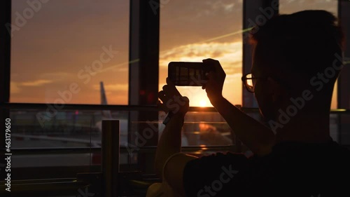 Passenger taking a photo of an airplane at the airport in the morning light