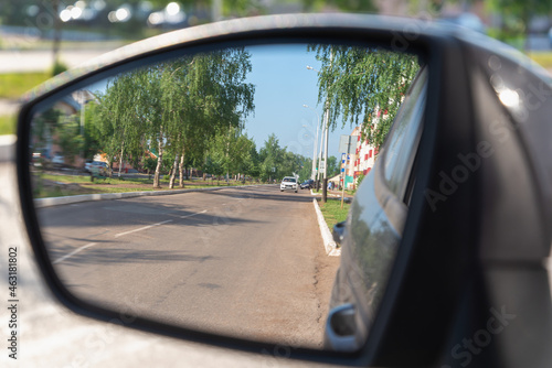 The side mirror of the car shows the street and the road. © Ilya