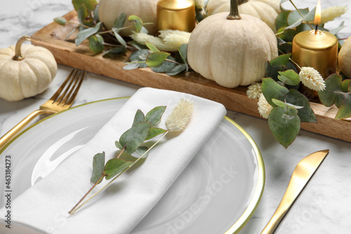 Festive table setting with autumn decor on white marble background  closeup