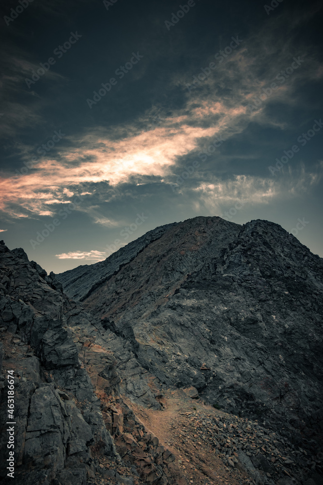 The dark stones of the mountains contrast with the bright cloud in the morning sky The dark stones of the mountains contrast with the bright cloud in the morning sky