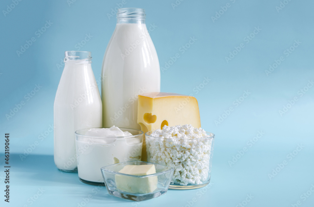Dairy products in close - up in transparent dishes on a blue background . Milk, kefir, sour cream, cheese, butter and cottage cheese in a glass container on a light background Dairy products in close - up in transparent dishes on a blue background . Milk, kefir, sour cream, cheese, butter and cottage cheese in a glass container on a light background