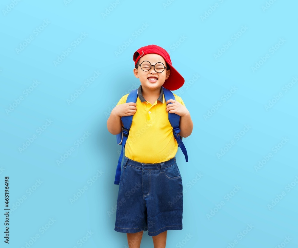 A cheerful child in a yellow brightly colored tshirt, eyeglasses, and a red cap. A kindergarten boy gets ready to go to travel or school. A cheerful child in a yellow brightly colored tshirt, eyeglasses, and a red cap. A kindergarten boy gets ready to go to travel or school.